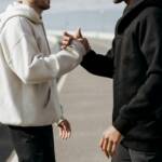 A Person in White Hoodie and Black Pants Holding Hands With a Person in Black Jacket